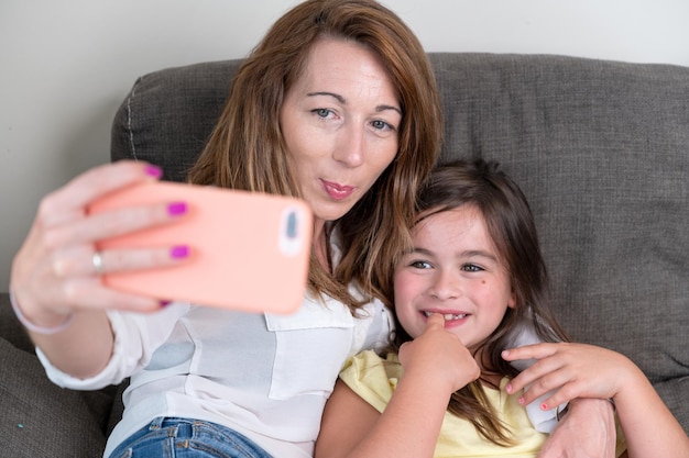 Foto madre e hija tomándose selfie en casa