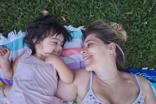 Madre e hija tumbadas en el césped disfrutando de la primavera