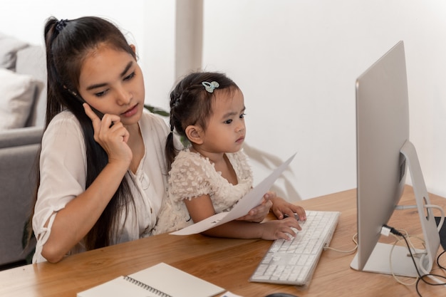 Madre e hija usando una computadora mientras trabajan desde casa