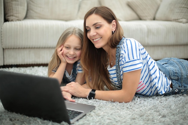 Madre e hija usando una computadora portátil en su hogar y tecnología