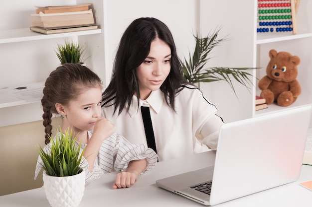 Madre e hija usando laptop e internet juntos en casa.