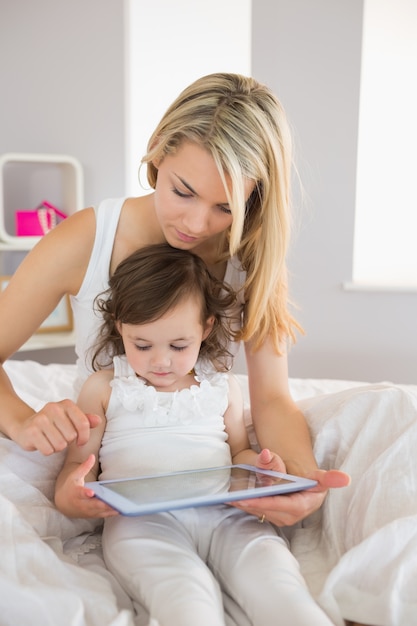 Madre e hija usando tableta digital en la cama