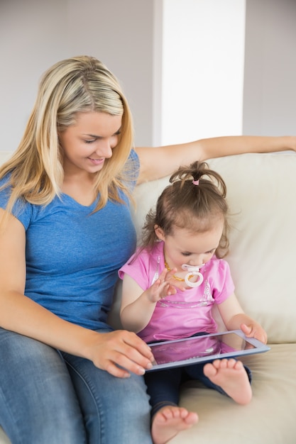 Madre e hija usando tableta digital en el sofá