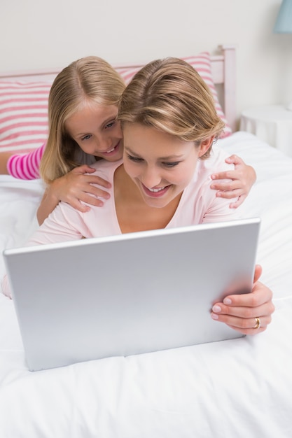 Madre e hija usando tableta juntos en la cama