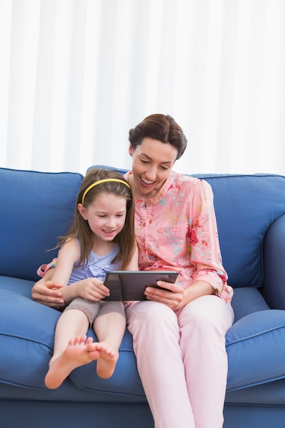 Madre e hija usando tableta en el sofá