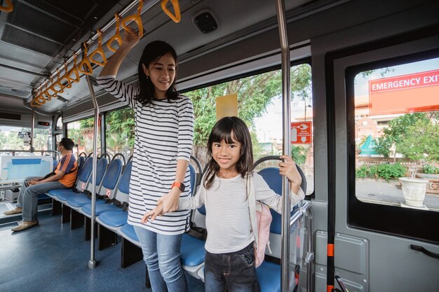 Madre e hija van a la escuela por la mañana en autobús público