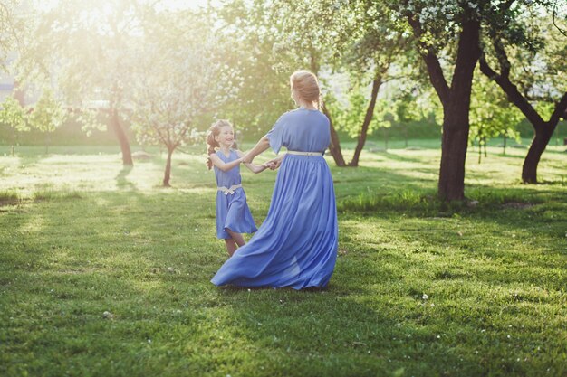 Madre e hija en vestidos en la naturaleza