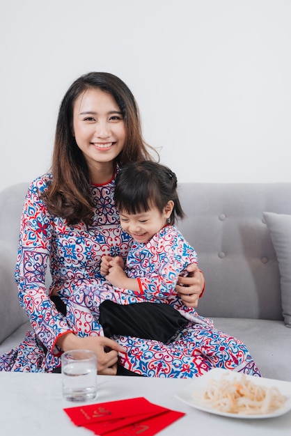 Madre e hija vietnamitas en traje tradicional Ao Dai, celebran el año nuevo en casa. Tet Holiday.