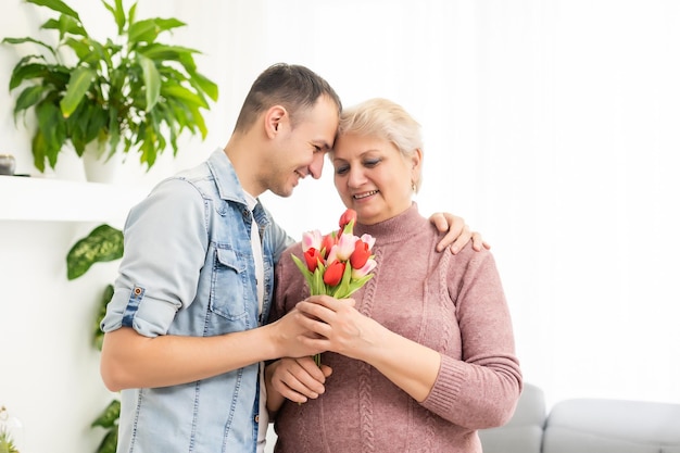 Madre e hijo adulto juntos, hijo dando un beso a la madre.