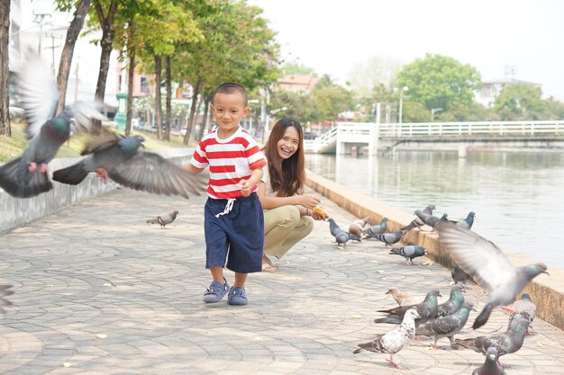Madre e hijo alimentando pájaros en el parque