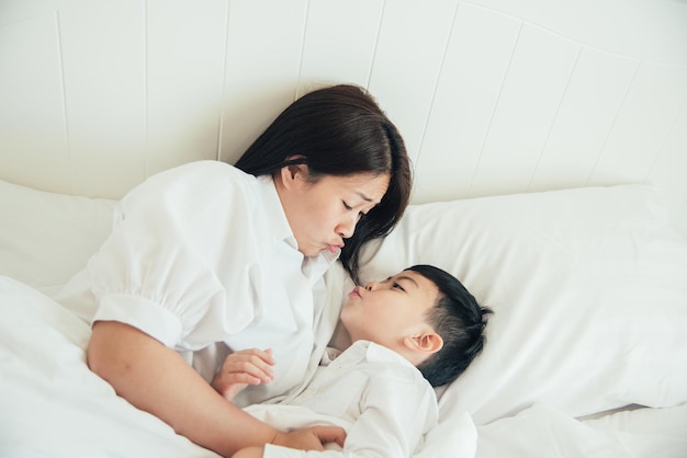 Madre e hijo arrugando los labios mientras están acostados en la cama en casa