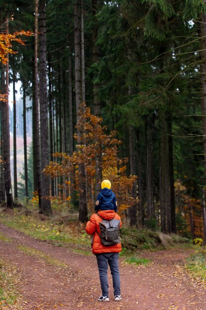 Madre e hijo caminan por el bosque en otoño