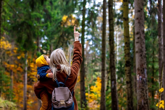 Madre e hijo caminan por el bosque en otoño