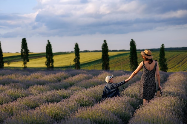 Madre e hijo caminan de la mano en un hermoso campo paisajístico con lavanda