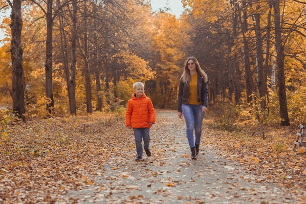 Madre e hijo caminando en el parque de otoño y disfrutando de la hermosa temporada de naturaleza otoñal