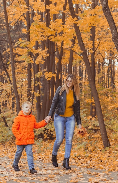 Madre e hijo caminando en el parque de otoño y disfrutando de la hermosa temporada de naturaleza otoñal