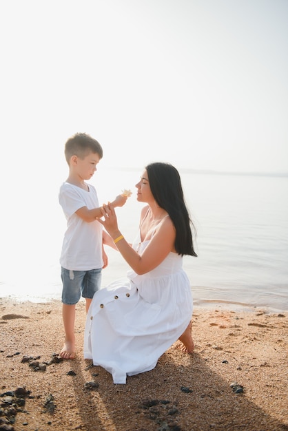 Madre e hijo caminando por la playa al atardecer