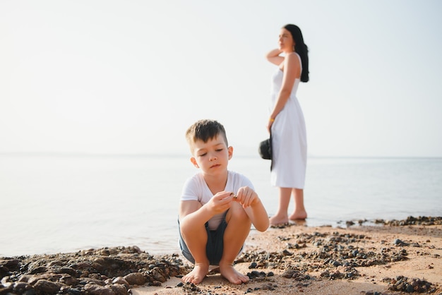 Madre e hijo caminando por la playa al atardecer