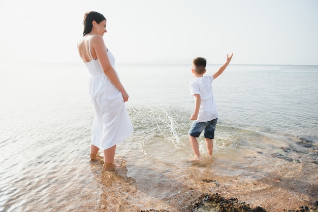 Madre e hijo caminando por la playa al atardecer