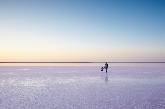 Madre e hijo caminando sobre una sal y salmuera de un lago rosa, na