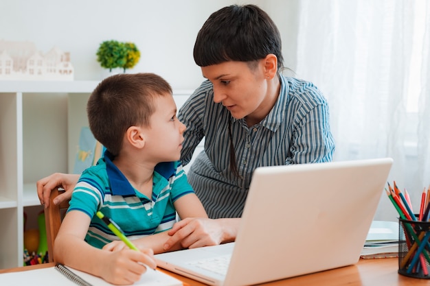 Madre e hijo en casa con una computadora portátil, aprendiendo