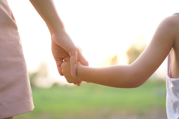 Madre e hijo cogidos de la mano en el fondo del atardecer