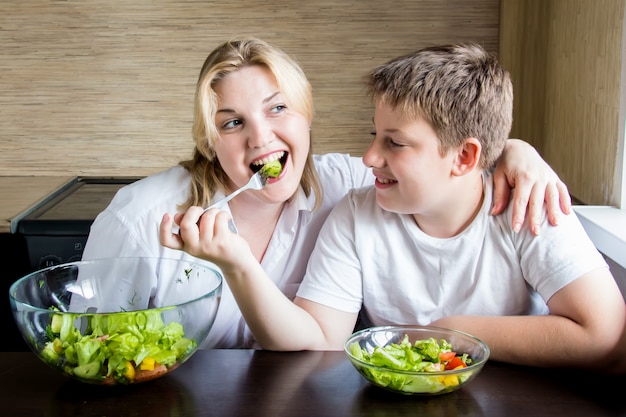 Madre e hijo comiendo ensalada y divirtiéndose.