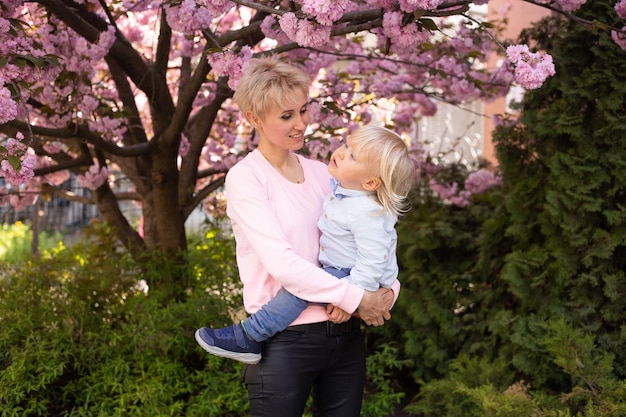 Madre e hijo se divierten en los florecientes jardines de Sakura Retrato mujer abrazando a un niño pequeño