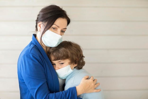 Foto madre e hijo enmascarados se sientan abrazando caras tristes