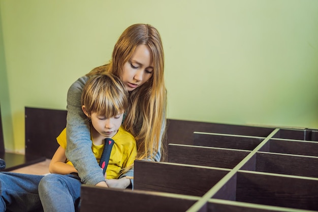 Madre e hijo ensamblando muebles Niño ayudando a su madre en casa Concepto de familia feliz