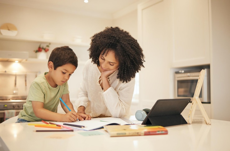 Foto madre e hijo y escritura para la educación en el hogar, aprendizaje electrónico y apoyo familiar para el desarrollo creativo. mamá y niño interracial con libros y dibujos para guía escolar en línea o enseñanza en tableta.