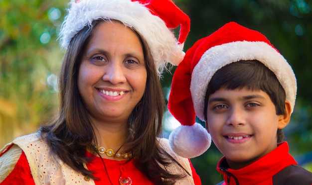 Madre e hijo con gorro de Papá Noel sonriendo y mirando a la cámara durante la temporada navideña