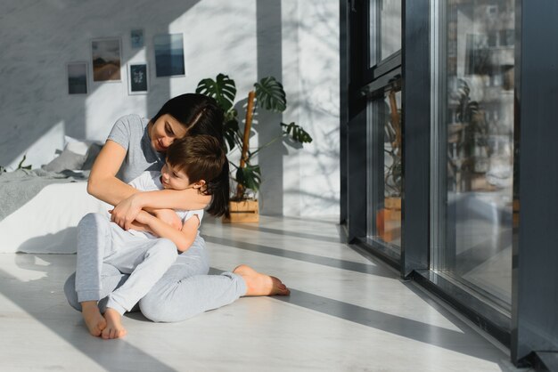 Madre e hijo graciosos en el suelo de la sala de estar