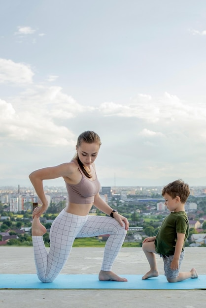 Madre e hijo haciendo ejercicio en el balcón en el fondo de una ciudad durante el concepto de amanecer o atardecer de un estilo de vida saludable