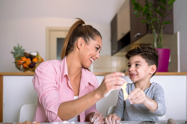 Madre e hijo hijo niño están cocinando galletas y divirtiéndose en la cocina