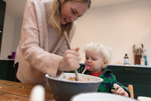 Madre e hijo horneando pasteles juntos niño lamiendo una cuchara