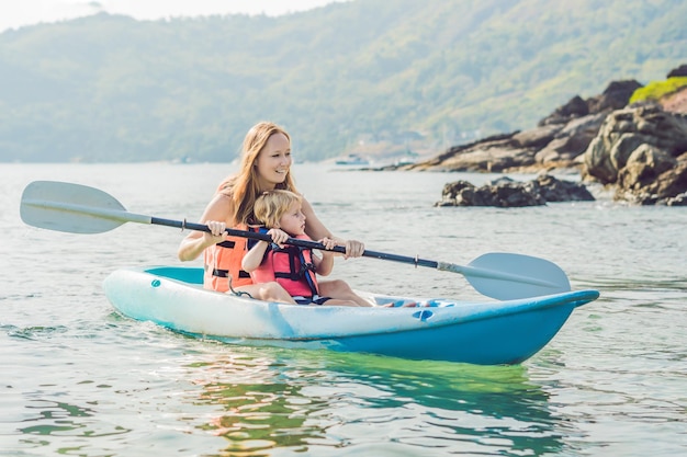 Madre e hijo en kayak en el océano tropical.