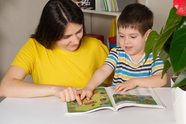 Madre e hijo leen el libro, miran las imágenes en las páginas.