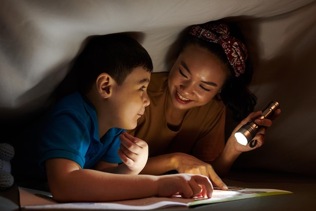 Madre e hijo leyendo bajo una manta