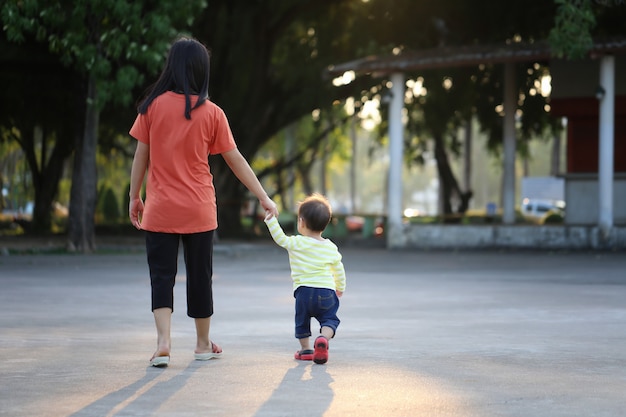 Madre e hijo con una mano para caminar en el parque.