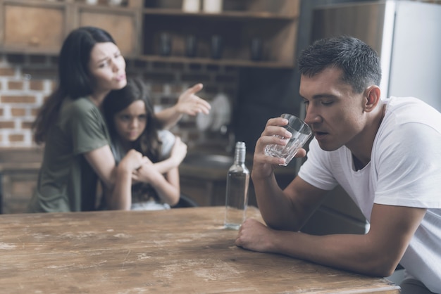 Foto madre e hijo miran al padre borracho en la cocina