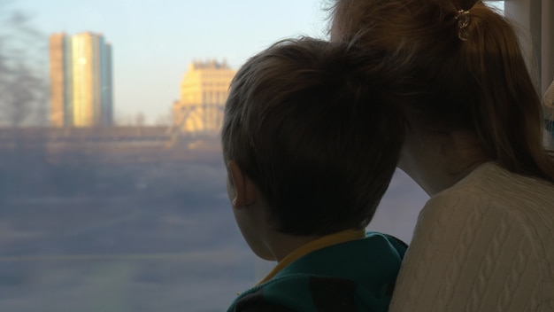 Madre e hijo mirando por la ventana del tren durante el viaje