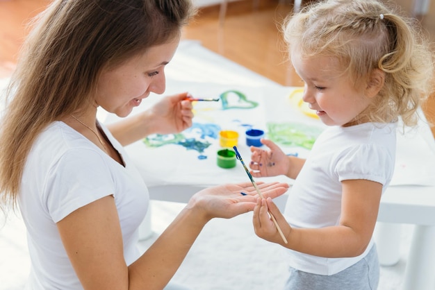 Madre e hijo niño pintando en casa familia creativa