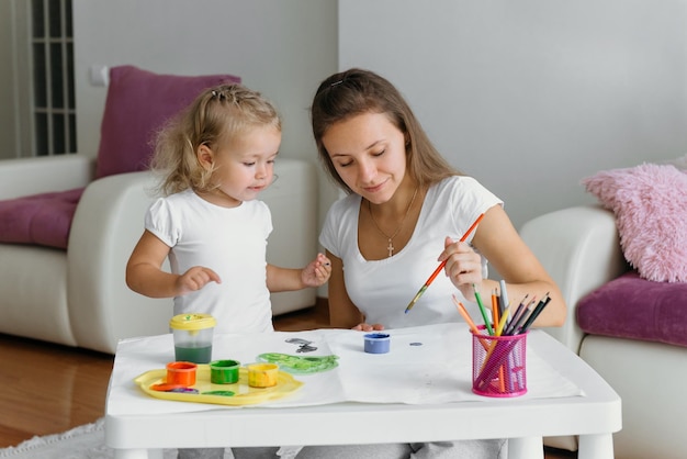 Madre e hijo niño pintando en casa familia creativa