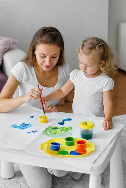 Madre e hijo niño pintando en casa familia creativa