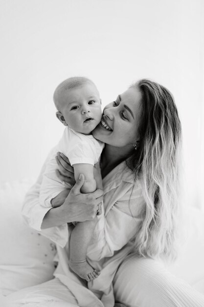 Foto madre e hijo niño sonriendo y jugando en la habitación de fondo blanco en el día soleado más feliz de todos los tiempos