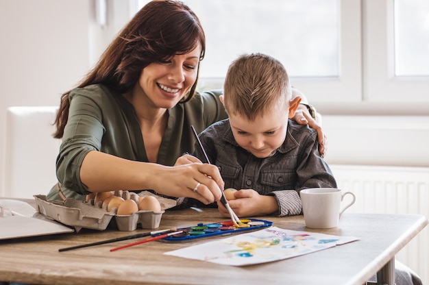 Madre e hijo pintando huevos de colores para la Pascua