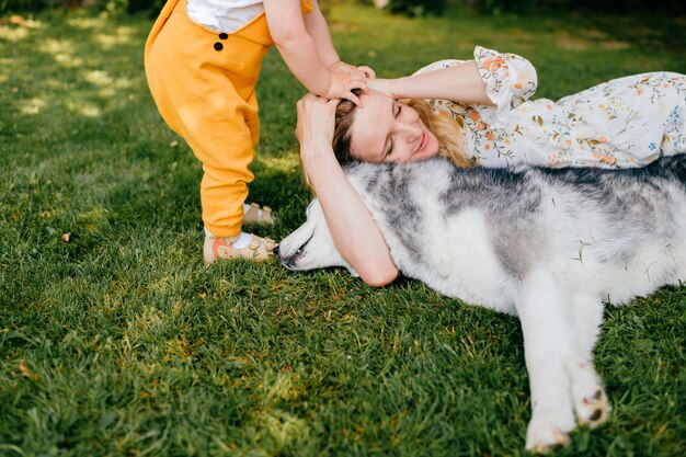 Madre e hijo posando con dos perros en la hierba