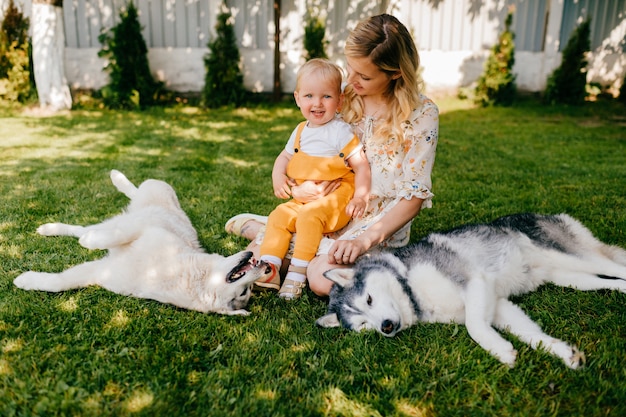 Madre e hijo posando con dos perros en la hierba