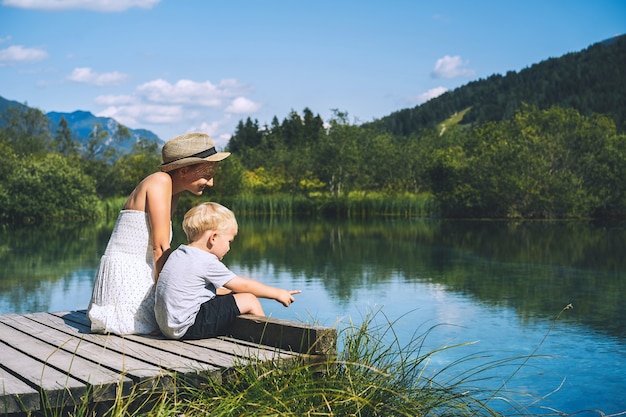 Madre e hijo en el puente de madera sobre la naturaleza del lago y las montañas Viajes concepto de estilo de vida familiar